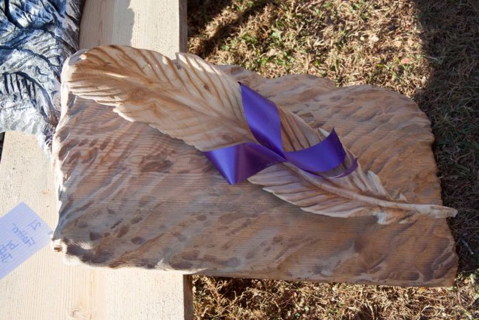 feather carving with purple ribbon
