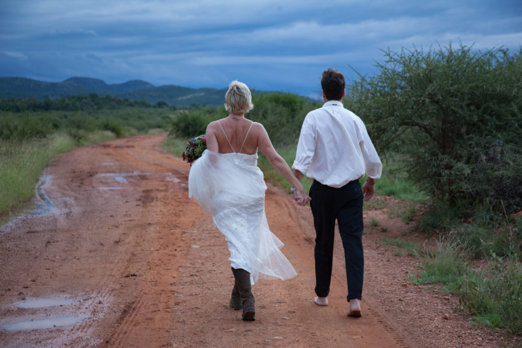 Bride and groom barefoot on dirt road on South African safari