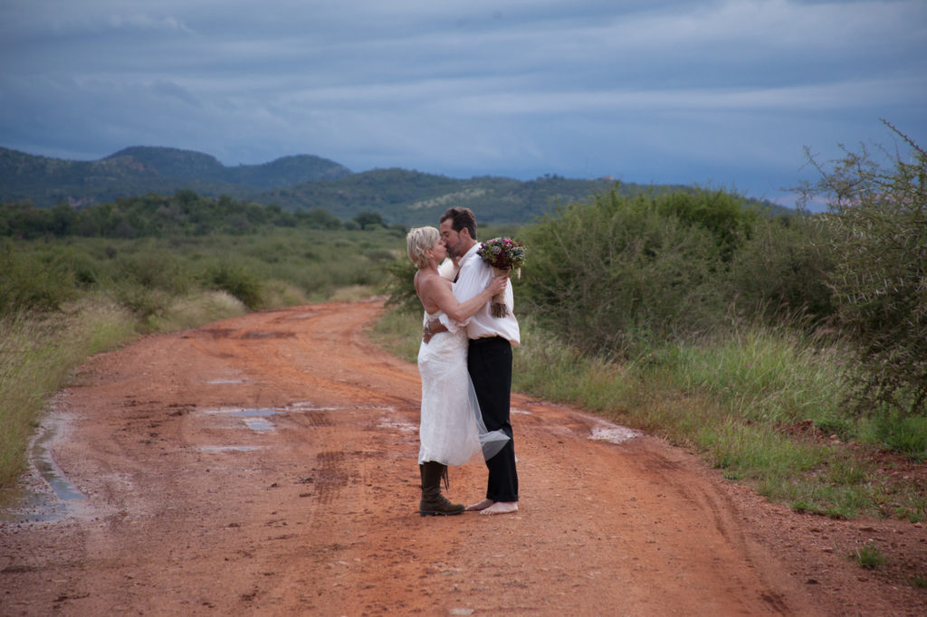 Bride and groom barefoot on dirt road on South African safari